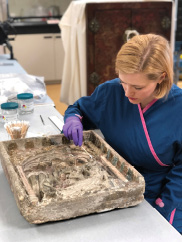 conservator cleans a piece of art